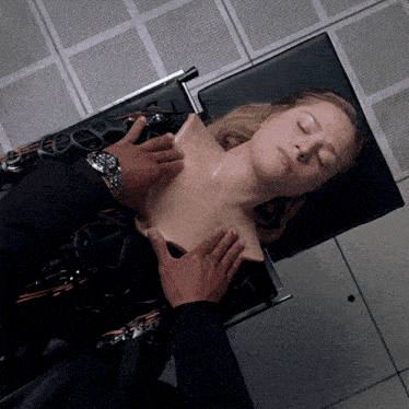 a woman is laying on a table with her eyes closed and a man is touching her chest