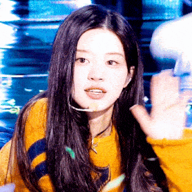 a close up of a woman wearing a yellow sweater and a microphone