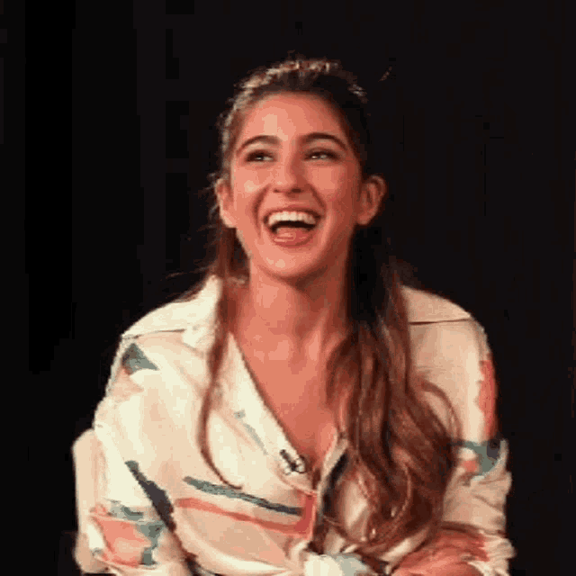 a woman in a floral shirt is laughing with her tongue out .