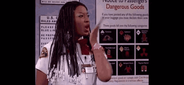 a woman is standing in front of a sign that says " notice to passengers dangerous goods "