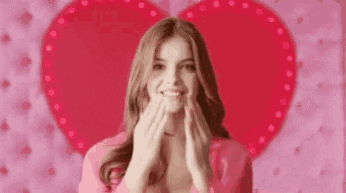 a woman is blowing a kiss in front of a heart shaped background .