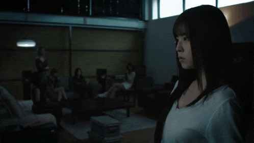a woman in a white shirt stands in front of a group of people