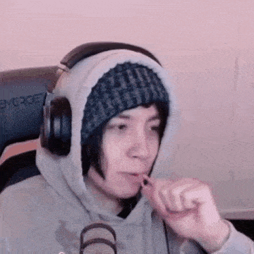 a person wearing headphones and a beanie is brushing their teeth in front of a microphone .