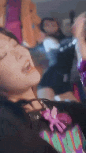 a woman is laying on a bed with her eyes closed and a pink pony on her necklace .