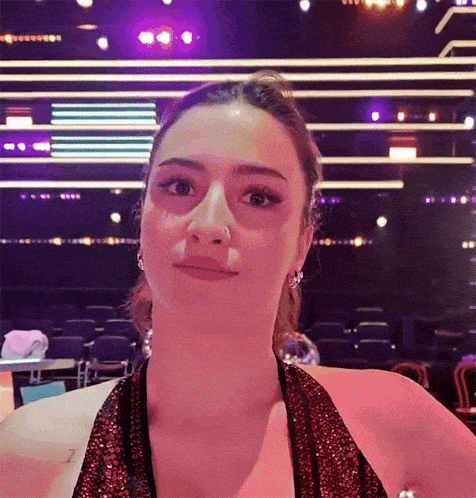 a woman in a red dress is standing in front of a stage with purple lights behind her .