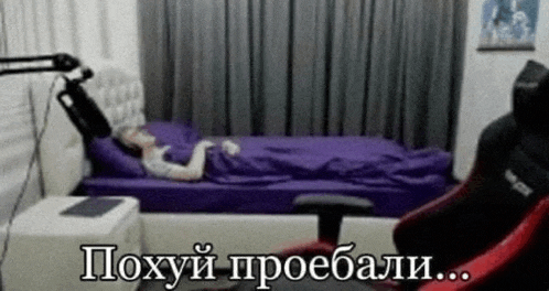 a woman is laying on a bed in a room with a microphone and a chair .