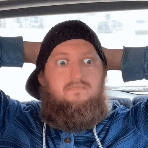 a man with a beard wearing a black hat and a blue shirt