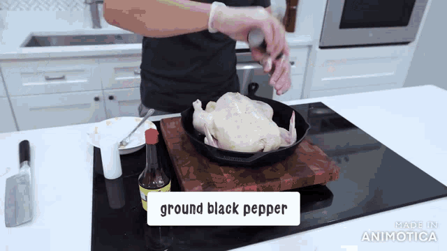 a person is putting ground black pepper on a chicken in a pan