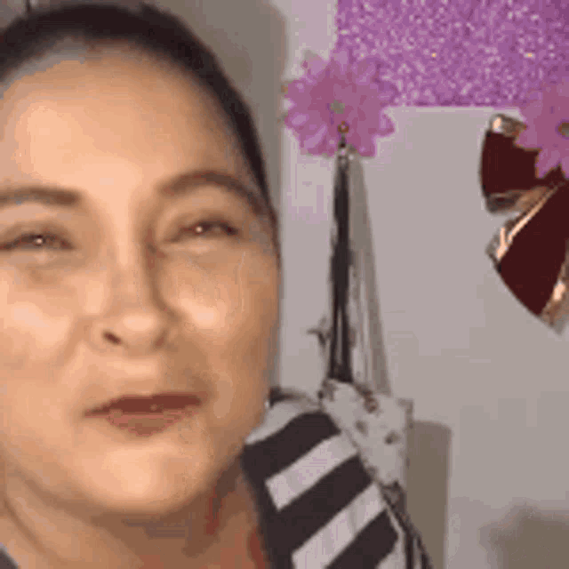 a close up of a woman 's face with a flower in the background
