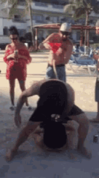a group of people are standing around a man holding a red cup on his head .