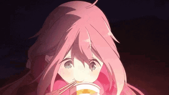 a girl with pink hair and blue eyes is eating noodles with chopsticks .