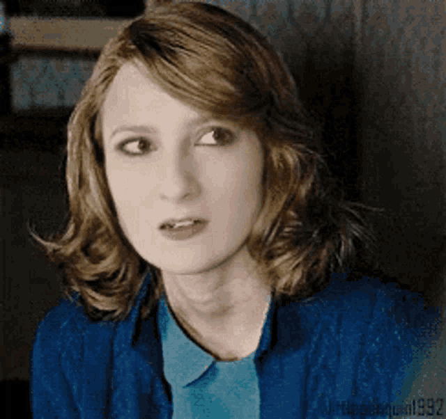 a woman with red hair is wearing a blue shirt and a blue sweater