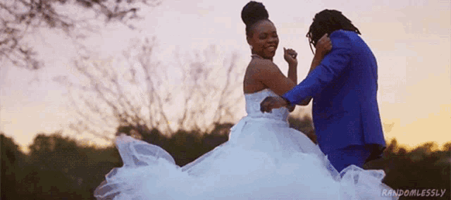 a bride in a white dress and a groom in a blue suit dancing