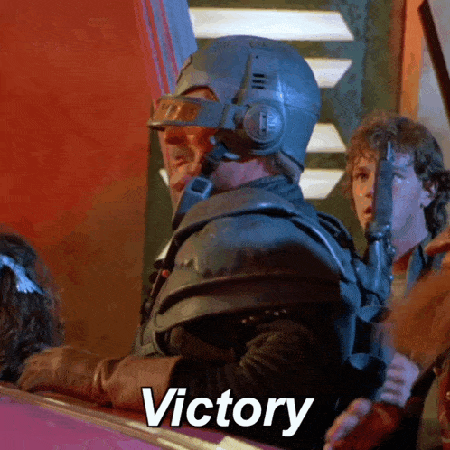 a man wearing a helmet and holding a gun says the word victory