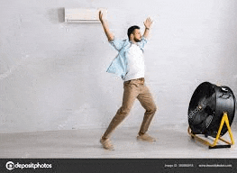 a man is standing in front of an air conditioner and a fan in a room .