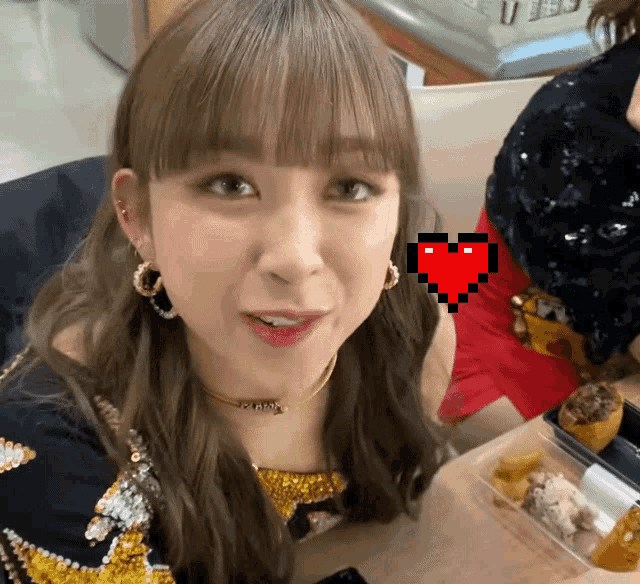 a woman sitting at a table with a pixelated heart in front of her
