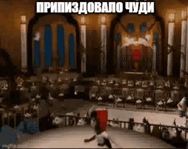a man is doing a trick on a stage in front of a crowd in a large room .