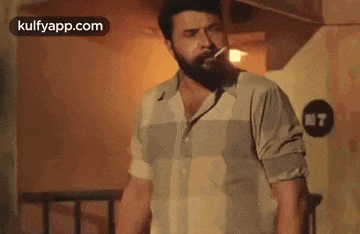 a man with a beard is smoking a cigarette in a room .