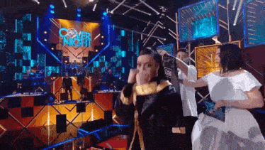 a group of people are standing on a stage in front of a large screen that says cover night .