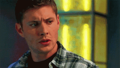 a man wearing a plaid shirt and a black shirt is making a surprised face .