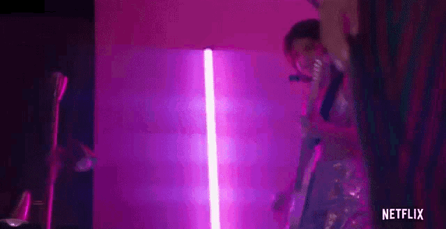 a person is standing in front of a purple light in a room .