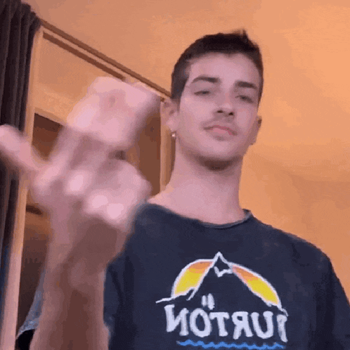 a young man wearing a t-shirt that says motau is waving his hand