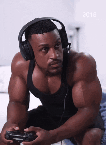 a muscular man wearing headphones is playing a video game in 2018