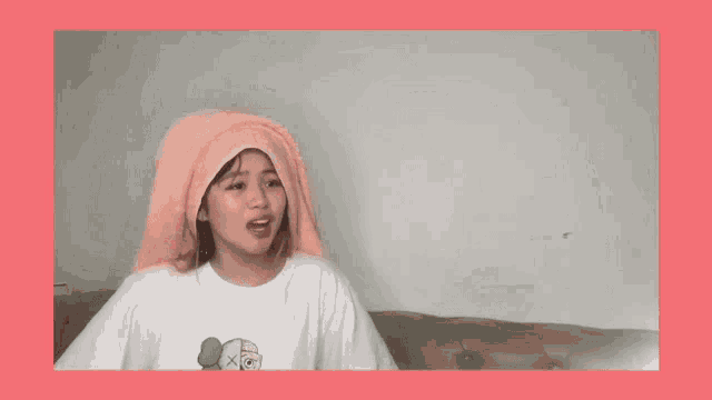 a woman with a towel wrapped around her head wearing a kaws t-shirt