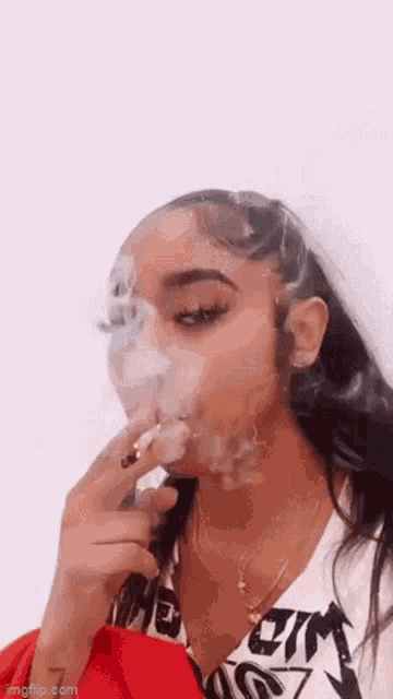 a woman is smoking a cigarette and blowing smoke into the air .