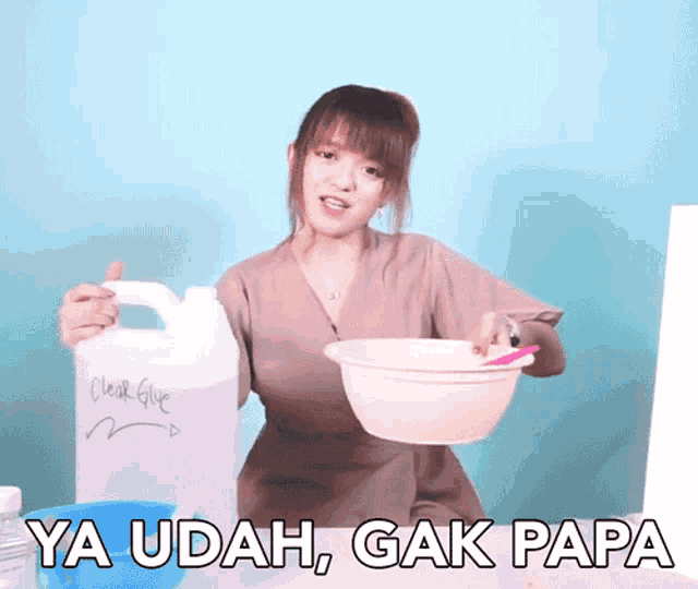 a woman is holding a bucket of clear glue and a bowl of liquid