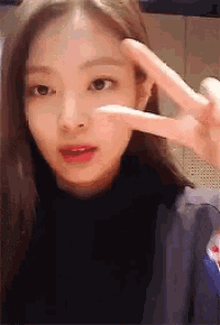 a close up of a woman giving a peace sign with her fingers .
