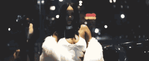 a woman in a white fur coat is standing next to a car .