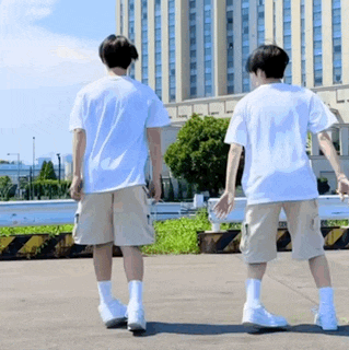 two young men are standing next to each other in front of a building