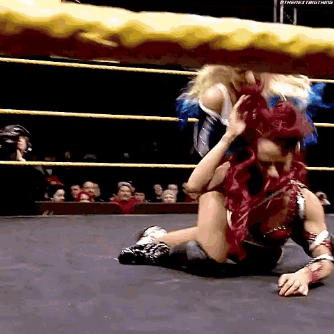 a woman with red hair is wrestling another woman in a wrestling ring