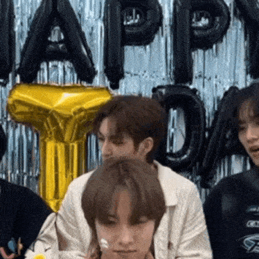 a group of young men are sitting in front of balloons that say happy birthday