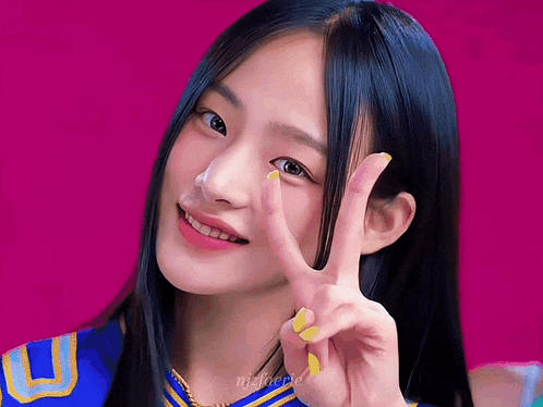 a girl with long black hair is smiling and giving the peace sign