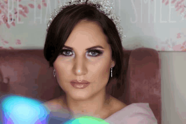 a woman wearing a tiara and earrings is sitting in a chair
