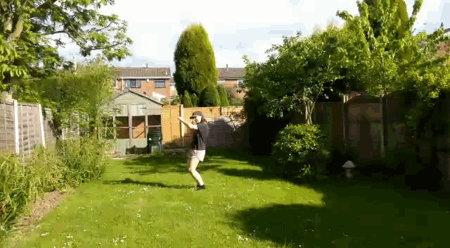 a man is dancing in a backyard in front of a greenhouse .