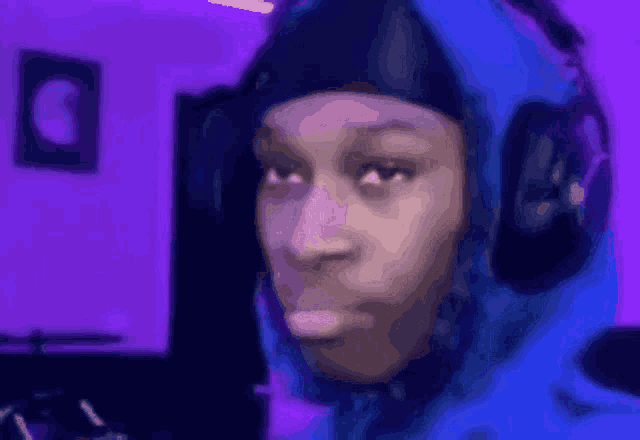 a man wearing headphones and a blue hoodie is making a face .