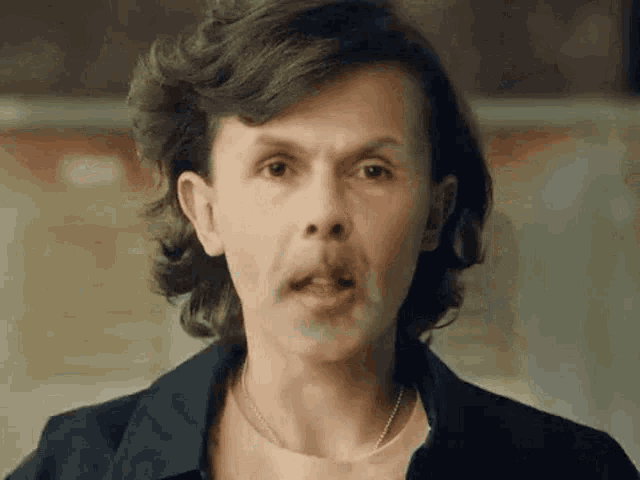 a man with long hair is making a funny face and making a funny face .