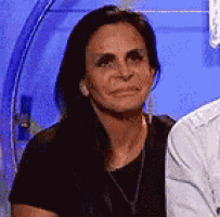 a woman in a black shirt is sitting next to a man in a white shirt and making a funny face .