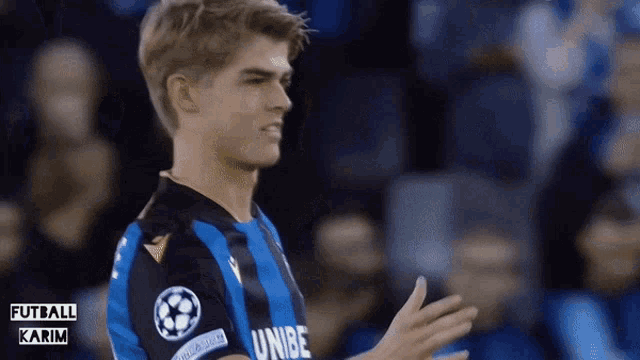 a soccer player wearing a blue and black uniform with the word unibe on it