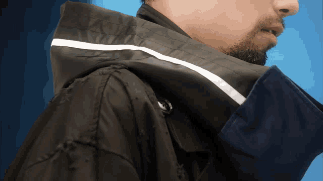 a man with a beard wearing a black jacket with a white stripe on the hood