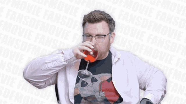 a man with glasses and a beard is drinking from a glass and smiling