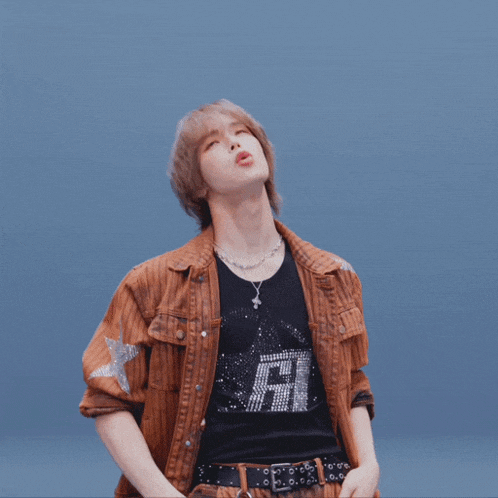a person wearing a brown jacket and a black shirt with the letter r on it