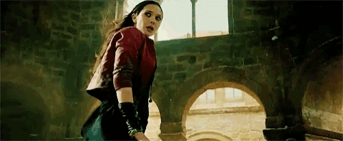 a woman in a red jacket and black skirt is standing in a building .