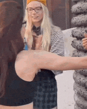 two women are standing next to each other and one is wearing glasses .