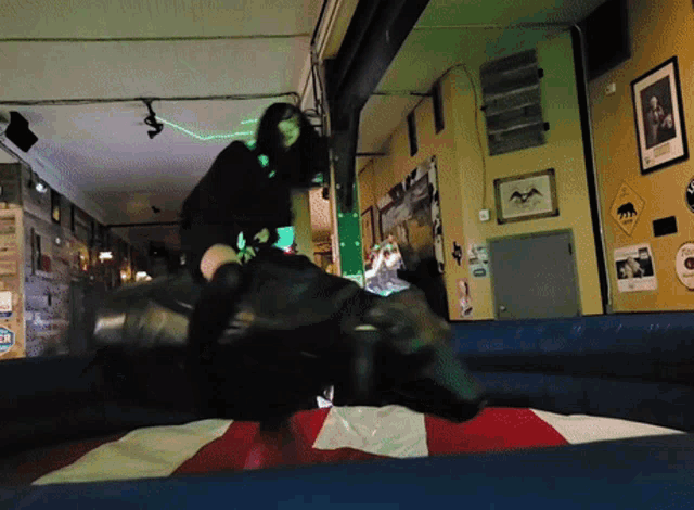 a woman is riding a bull in a room with a sign that says ' beer ' on the wall