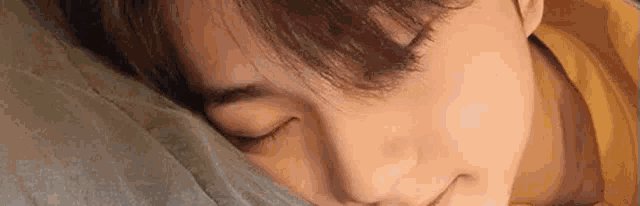 a close up of a person sleeping on a bed with their eyes closed .