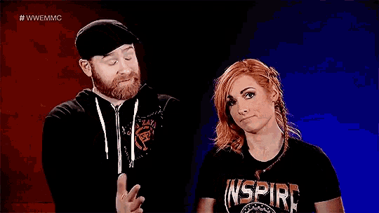 a man and a woman are standing next to each other in front of a red and blue background .